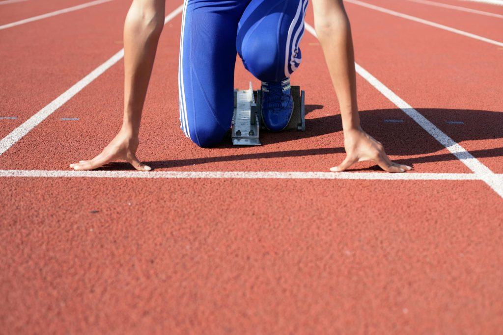 Athlete in starting blocks poised for a sprint on an outdoor track.
